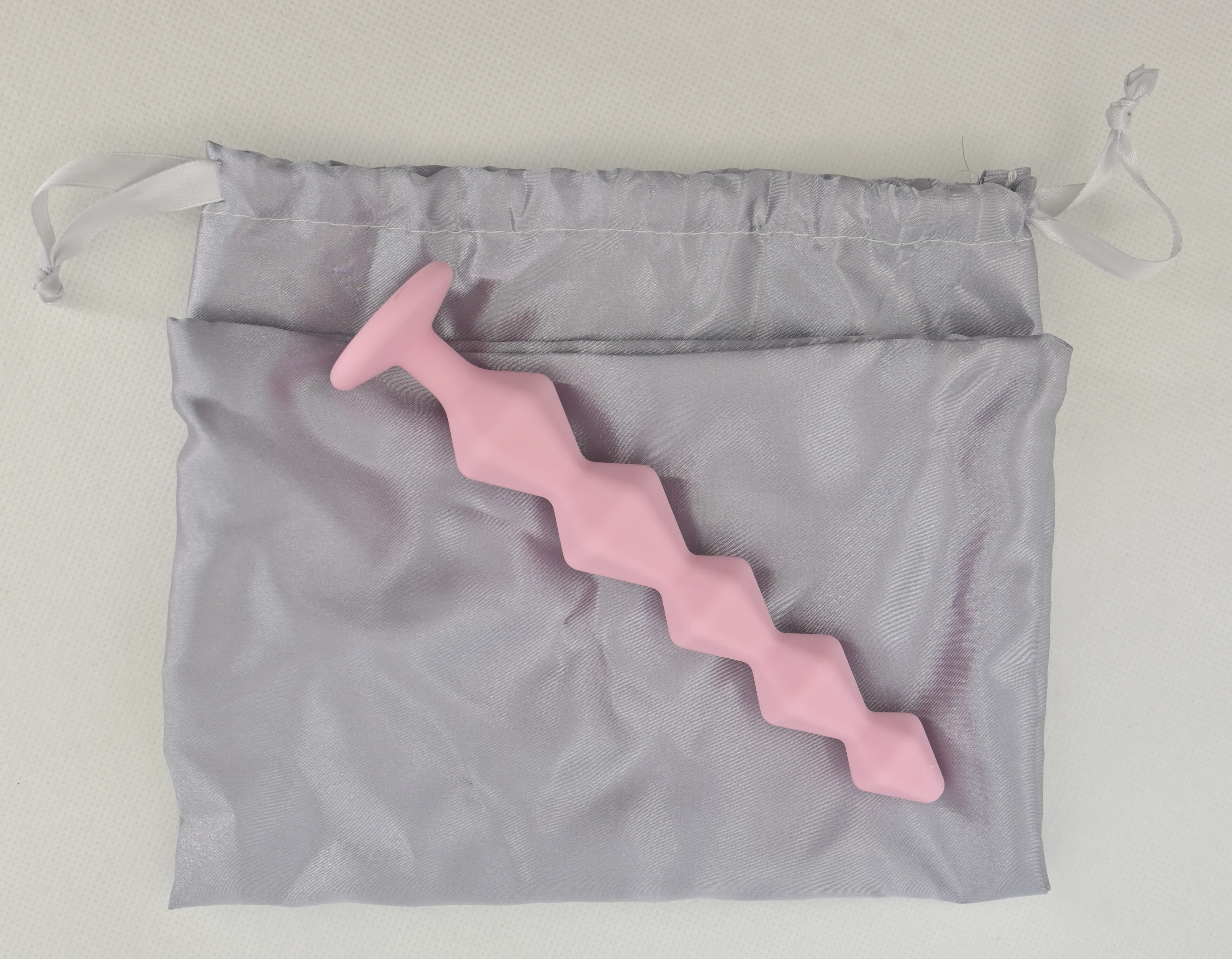 Розовая анальная цепочка на сером мешочке